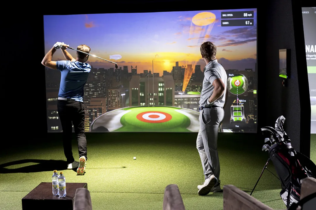 Two players enjoying Trackman bay hire with Bullseye game on the big screen